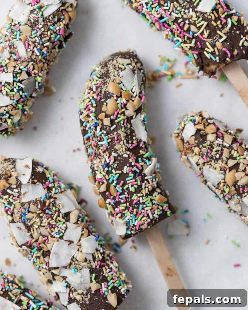 Frozen Chocolate Banana Bites 14 banana pop coated in sprinkles laid out on a flat parchment paper