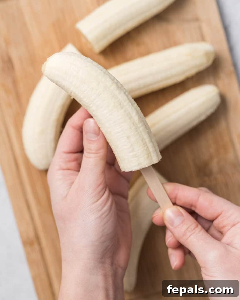 Frozen Chocolate Banana Bites 6 hand inserting a popsicle stick into banana