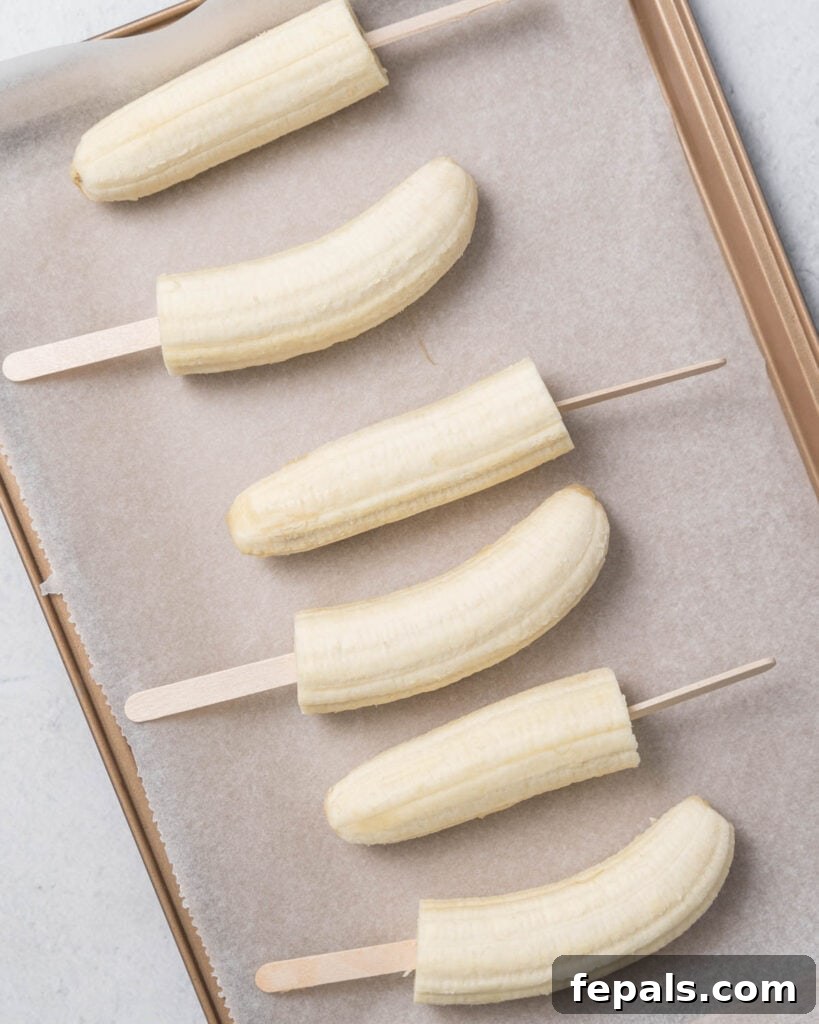Frozen Chocolate Banana Bites 7 banana pops added over parchment paper on a pan to be frozen