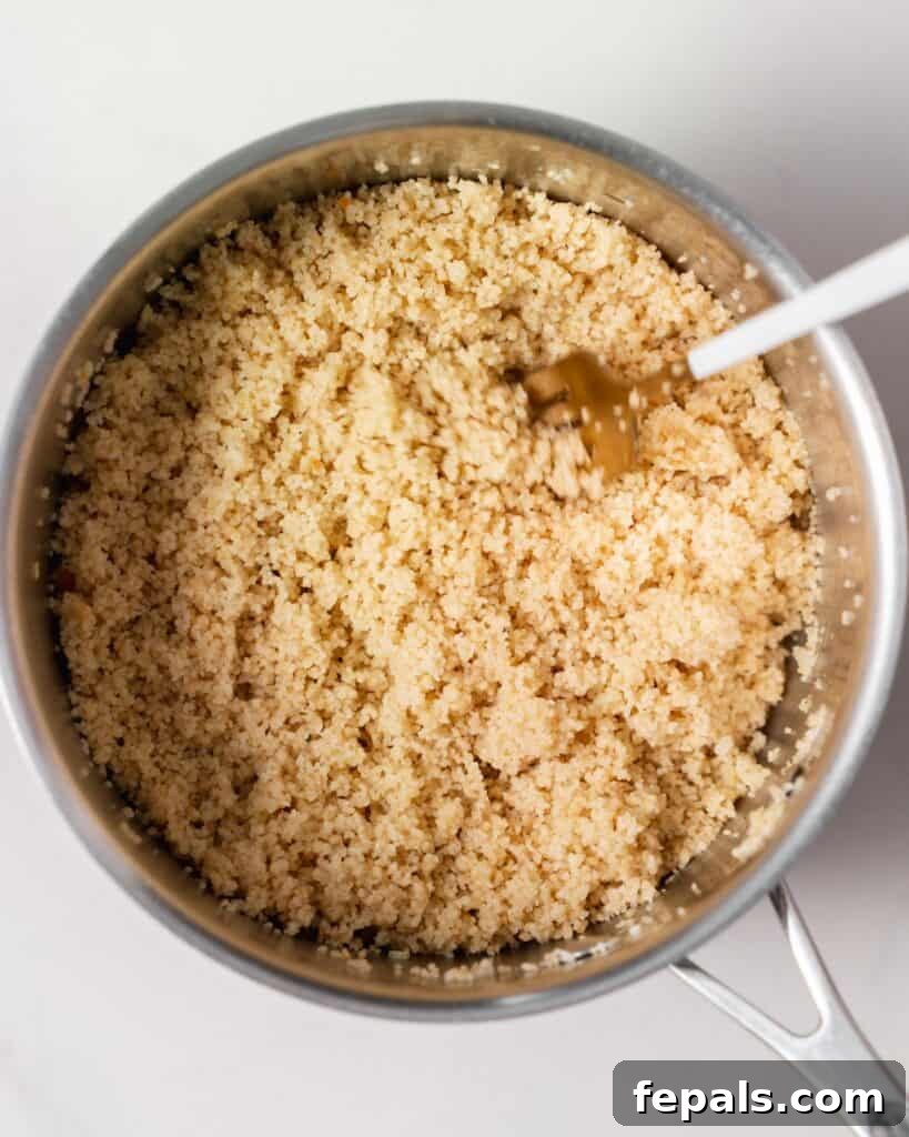 Fluffing cooked couscous with a fork.
