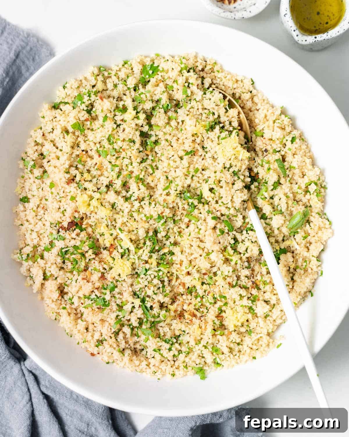 Couscous garnished with herbs and served with a large serving spoon.