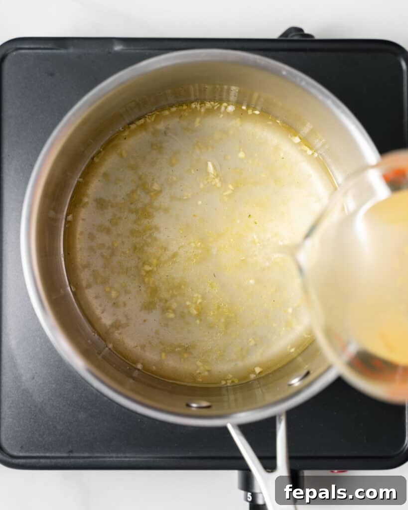 Pouring broth in a large pot with sautéed garlic.