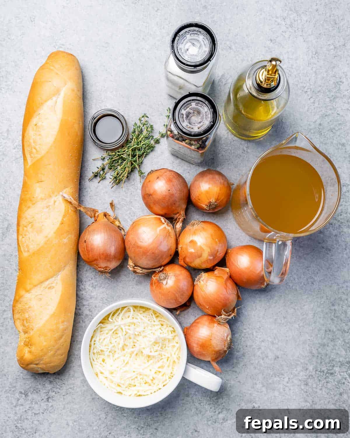 Effortless French Onion Elegance 4 Baguette on a counter with onions, broth, thyme and grated cheese.