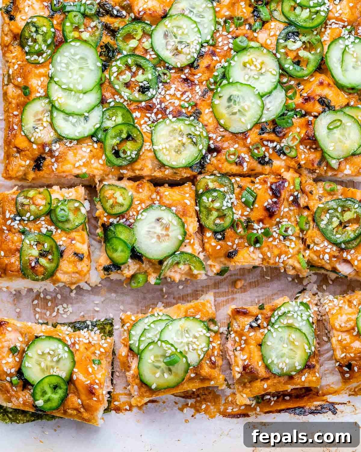 Ultimate Salmon Sushi Bake 2 Overhead view of salmon sushi bake topped with sliced cucumber and jalapeños.