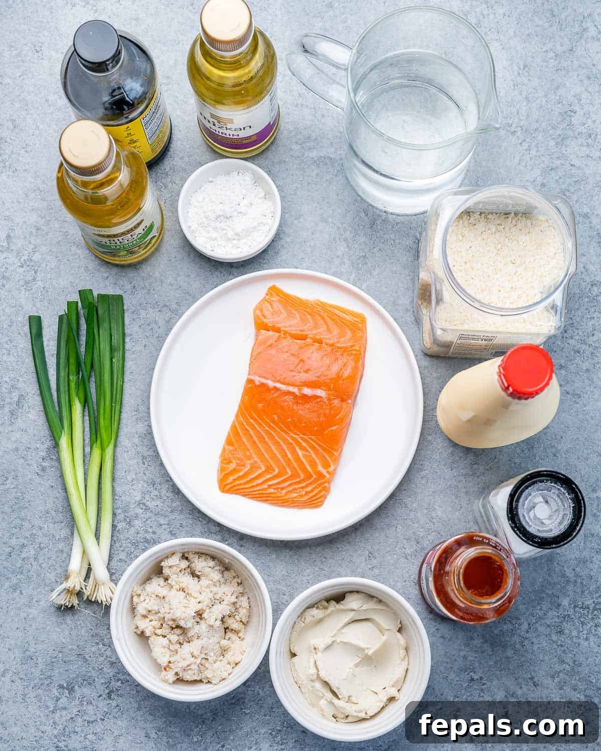 Ultimate Salmon Sushi Bake 4 Raw salmon on a plate near green onions, bowls of mayo and cream cheese, and seasoning like rice vinegar, soy sauce and sriracha sauce.