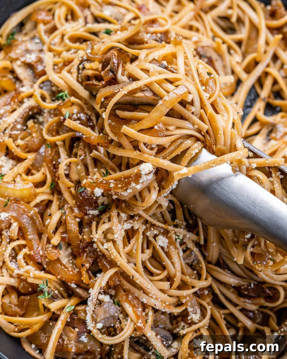 Caramelized Onion and Gruyere Pasta 3 Tongs serving French onion pasta with caramelized onions and mushrooms.