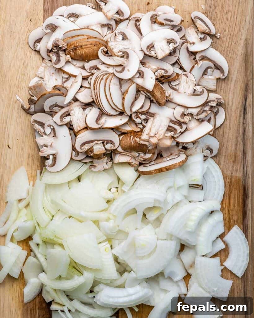 Caramelized Onion and Gruyere Pasta 5 Chopped onion and mushrooms on a cutting board, prepped for cooking.