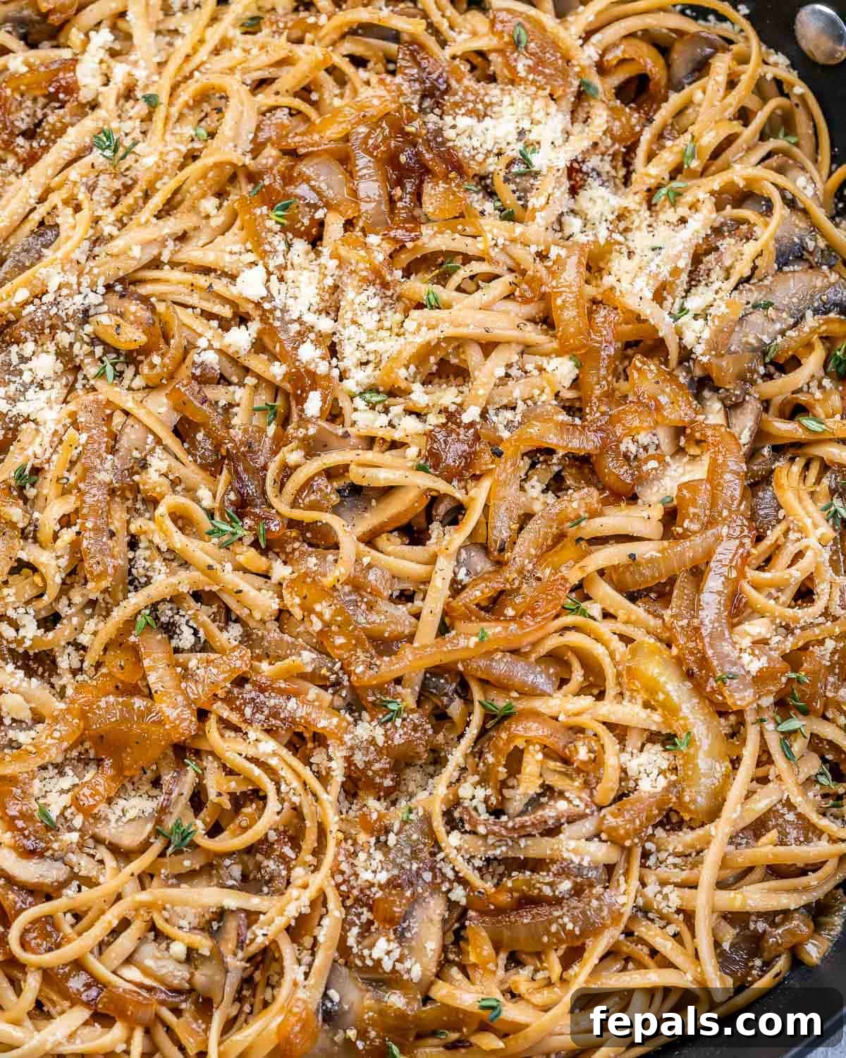 Caramelized Onion and Gruyere Pasta 9 Closeup view of French onion pasta cooked in a skillet, topped with fresh herbs.