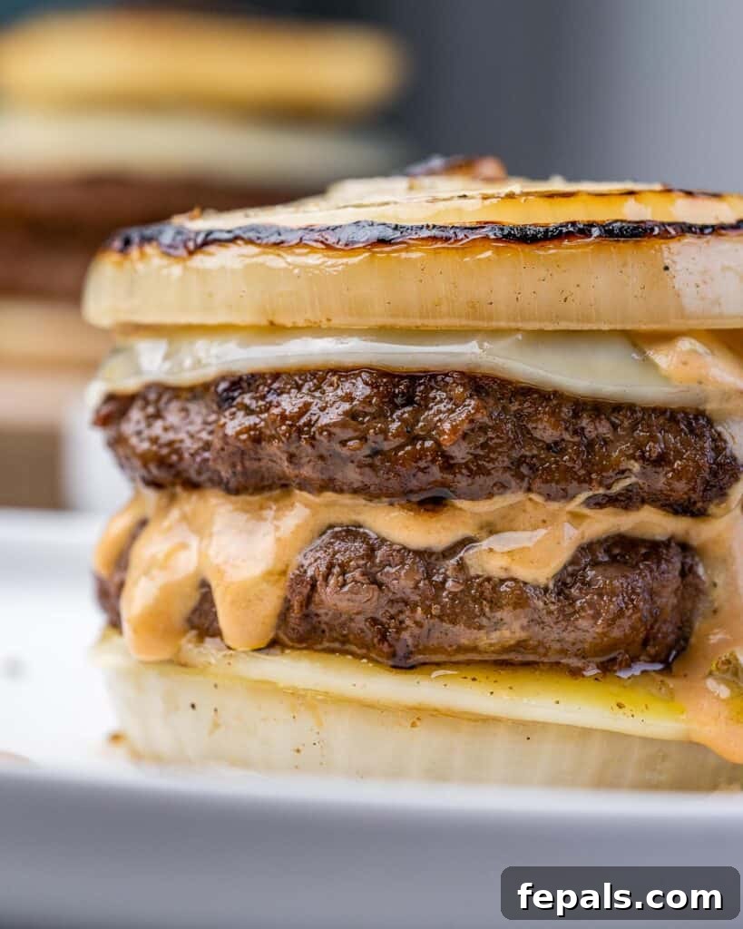 The Spectral Sailor Burger 3 close up side shot of flying dutchman burger on a plate with sliced onion buns and melted cheese slices