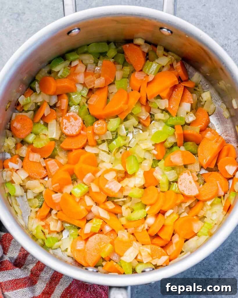 Veggies (carrots, celery, onion, garlic) sautéing in a soup pot, releasing their aromas.