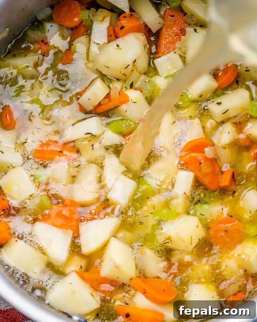 Adding vegetable broth to sautéed veggies in a soup pot.