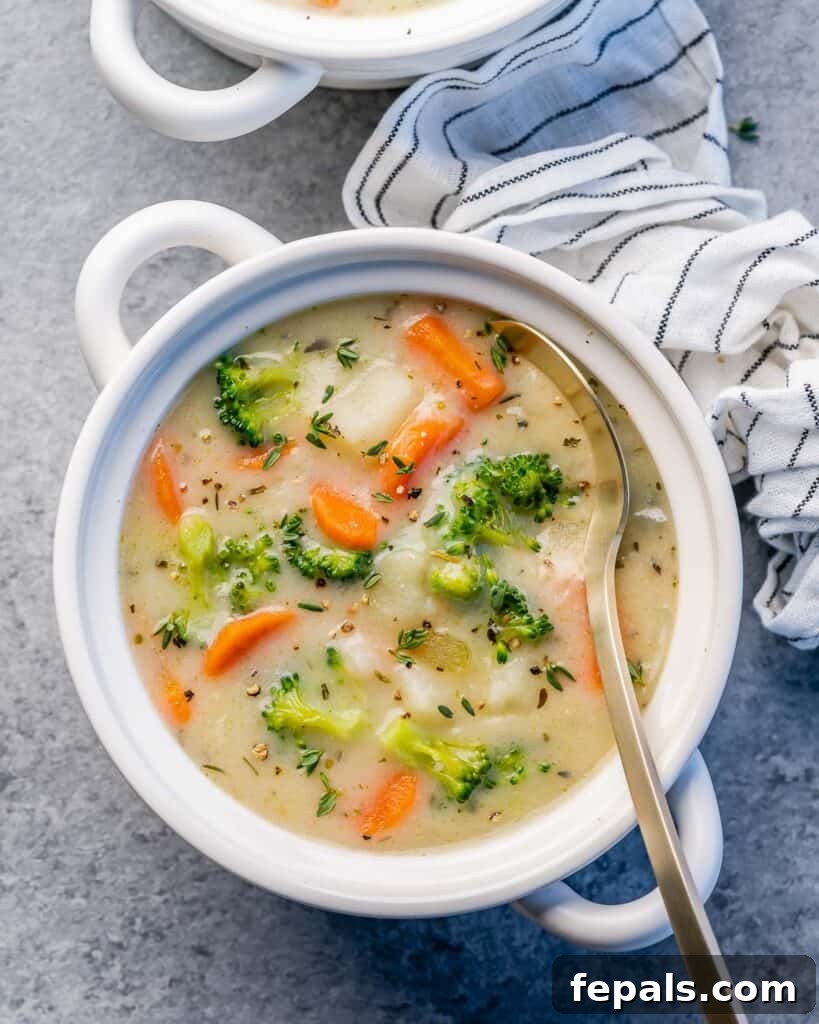 A bowl of creamy vegetable soup with a spoon, ready to be enjoyed.