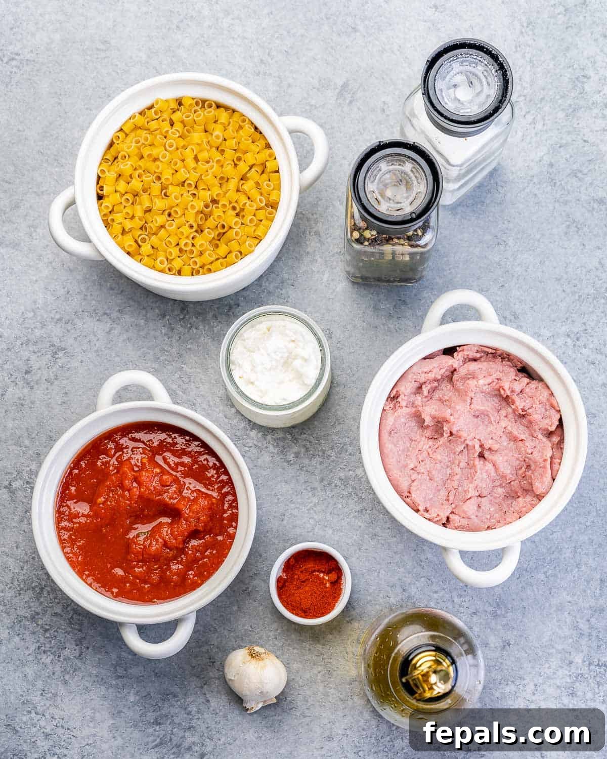 Creamy Cottage Cheese Pasta 4 Raw ground turkey in a bowl near other bowls of uncooked pasta, crushed tomatoes, cottage cheese and olive oil.