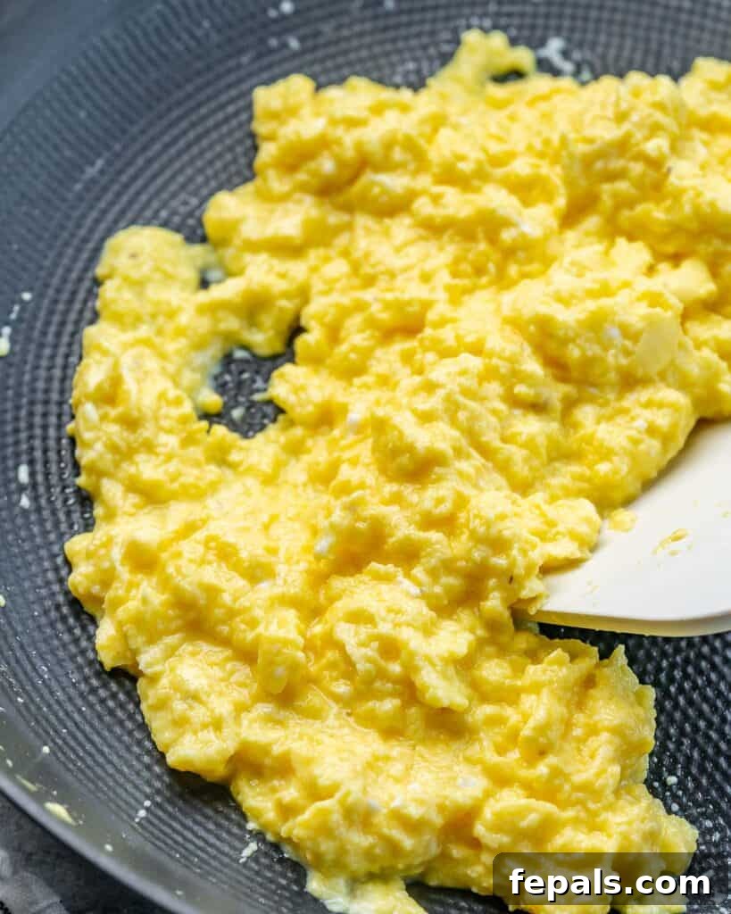Creamy Protein Scramble 7 Using a spatula to cook eggs in a pan.