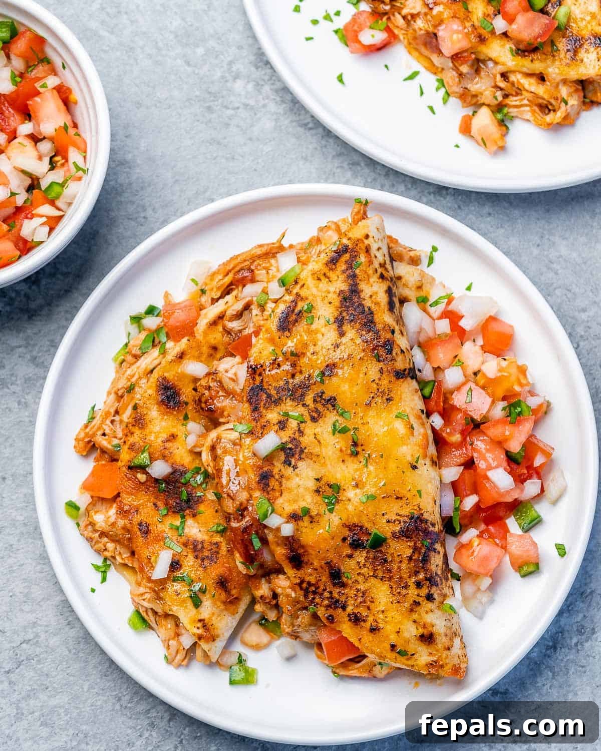 Crispy Birria Chicken Dipping Tacos 2 Üstten görünüm, iki tavuk birria tacosunun bulunduğu yuvarlak beyaz bir tabak, kişniş ve limonla süslenmiş.