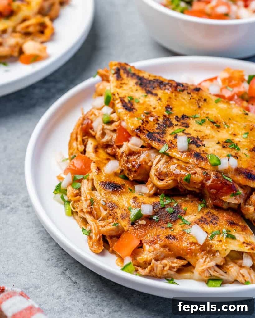 Crispy Birria Chicken Dipping Tacos 9 Beyaz bir tabakta birkaç tavuk Birria tacosunun yandan çekimi, zengin dolguyu ve çıtır kenarları gösteriyor.