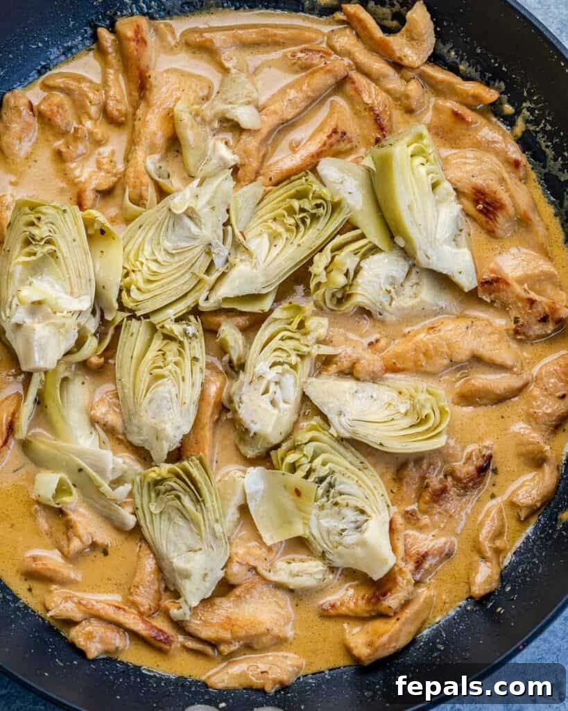 Creamy Chicken Artichoke Delight 7 artichoke added over the creamy chicken sauce on a black skillet
