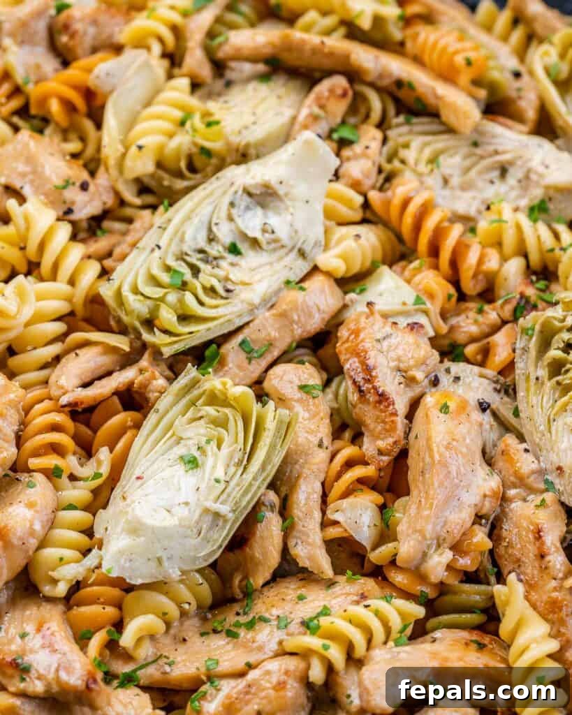 Creamy Chicken Artichoke Delight 10 close up multi-colored pasta in a dish artichoke and chicken slices