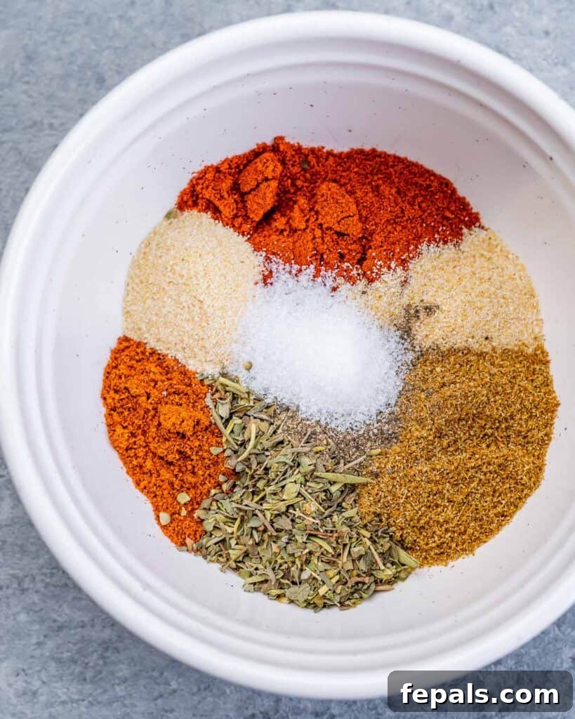 A close-up view of various spices being mixed together in a small, elegant white bowl with a spoon.
