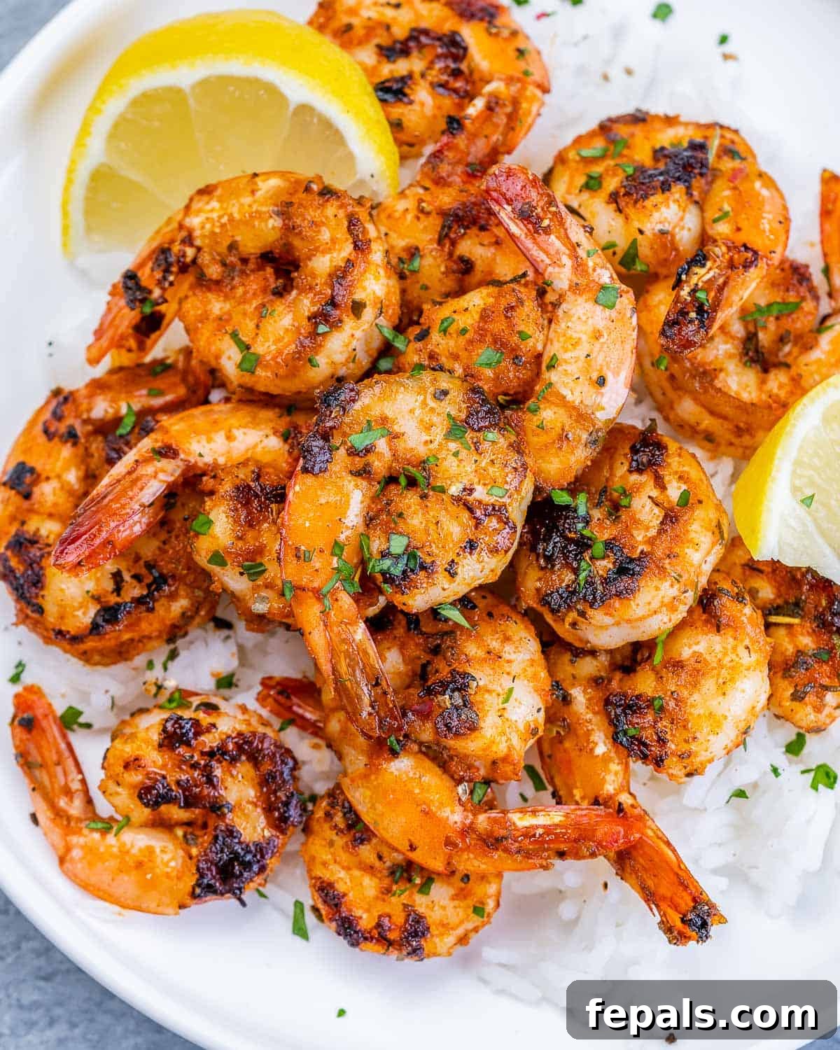A vibrant display of blackened shrimp served elegantly over fluffy white rice, artfully garnished with bright lemon wedges, ready to be enjoyed.