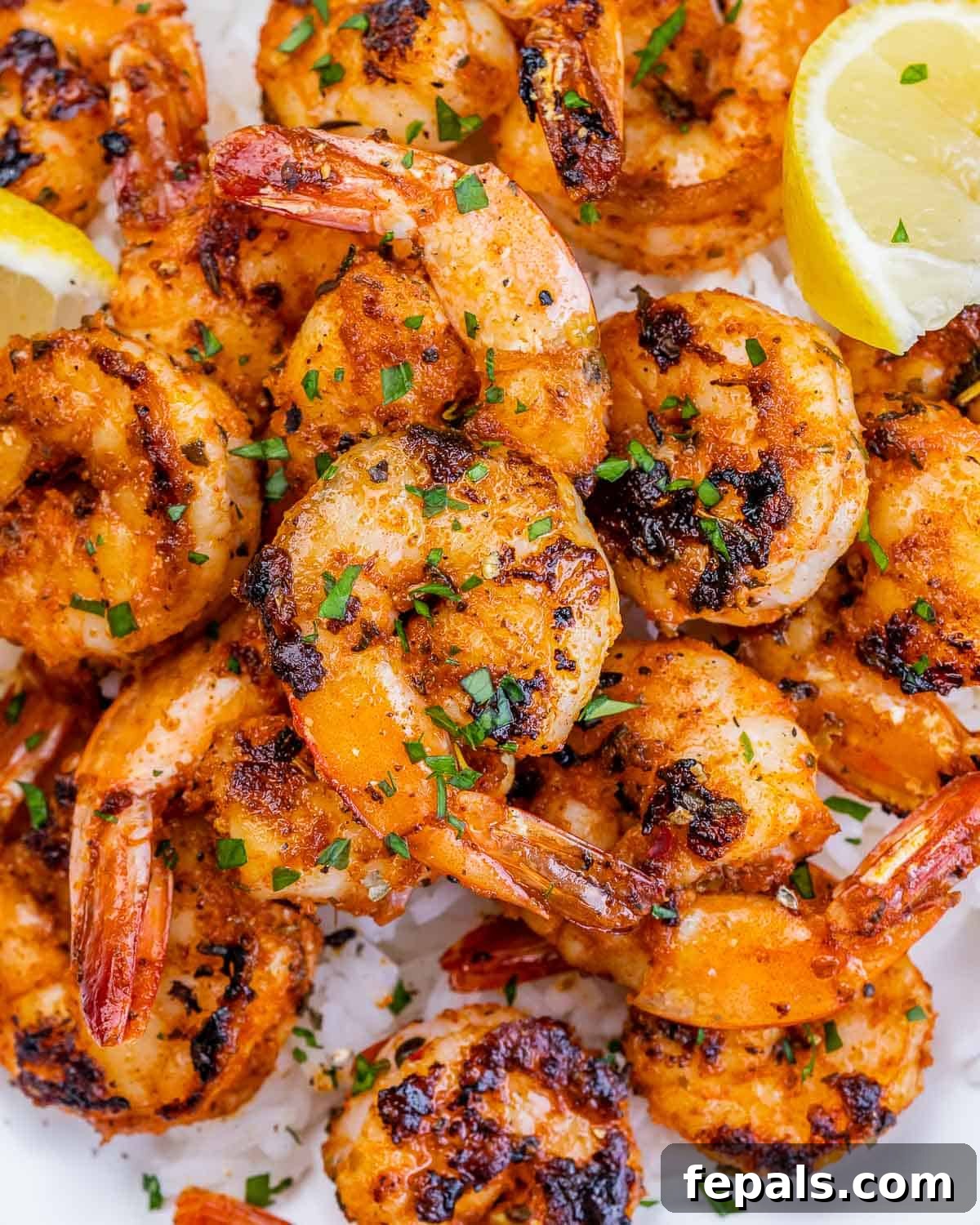 A close-up of beautifully cooked blackened shrimp, garnished with vibrant fresh parsley, presented on a simple white background.