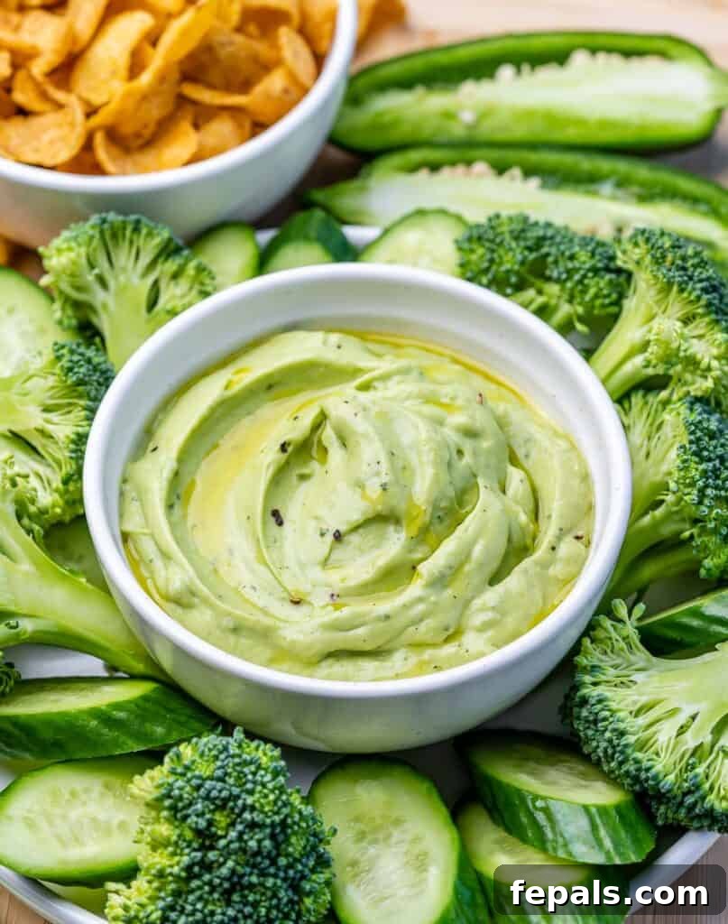 side shot of green veggies by a bowl of green avocado ranch dip 