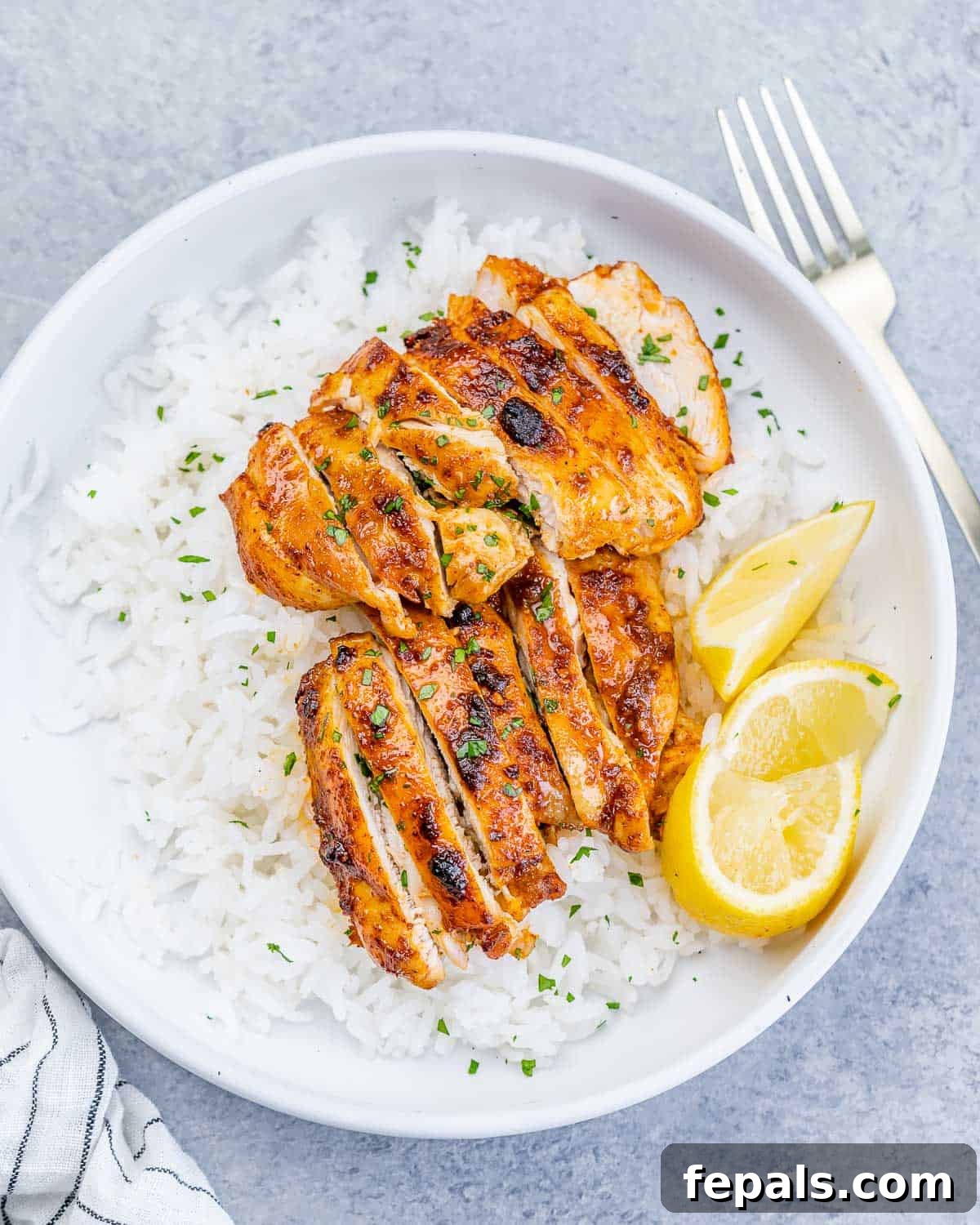 Crispy Air Fryer Boneless Chicken Thighs 2 Top view of a round white bowl with steamed white rice and sliced air-fried boneless chicken thighs.