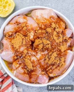 Adding taco seasoning to raw chicken thighs in a bowl.
