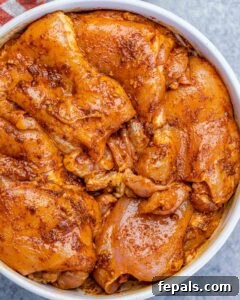 Chicken thighs marinating in a white bowl.