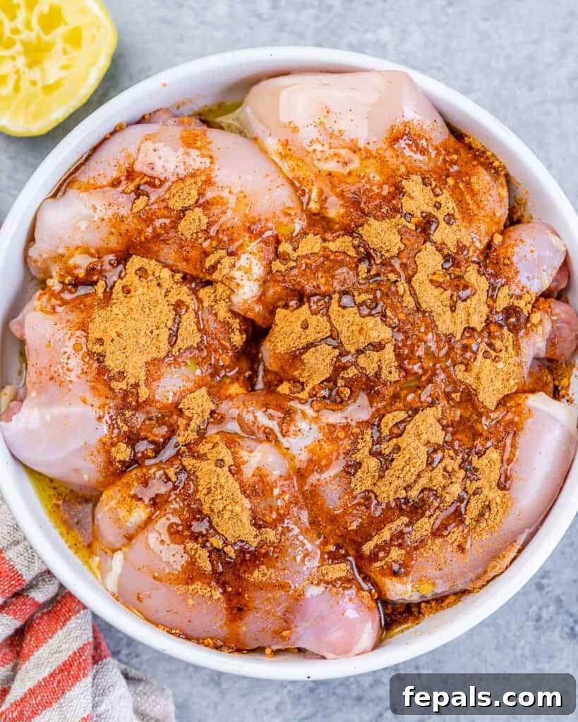 Crispy Air Fryer Boneless Chicken Thighs 5 Adding taco seasoning to raw chicken thighs in a bowl.