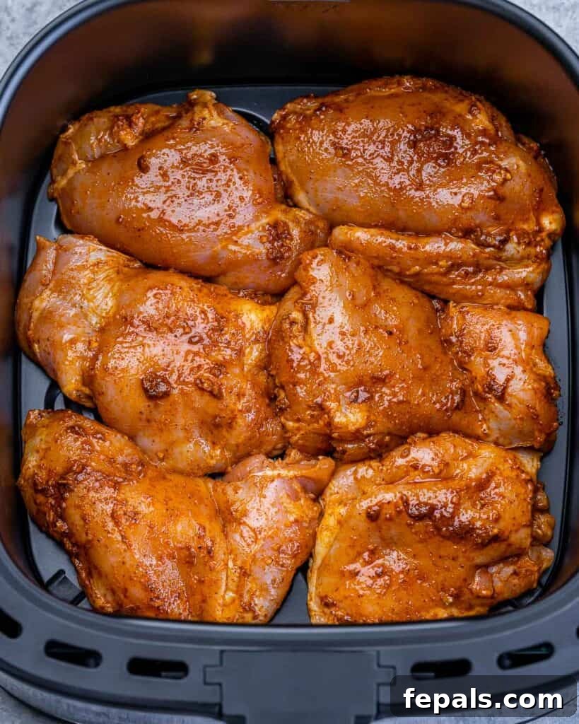 Crispy Air Fryer Boneless Chicken Thighs 7 Seasoned chicken thighs cooking in an air fryer.