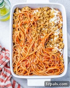 Assembling million dollar spaghetti in a casserole dish.