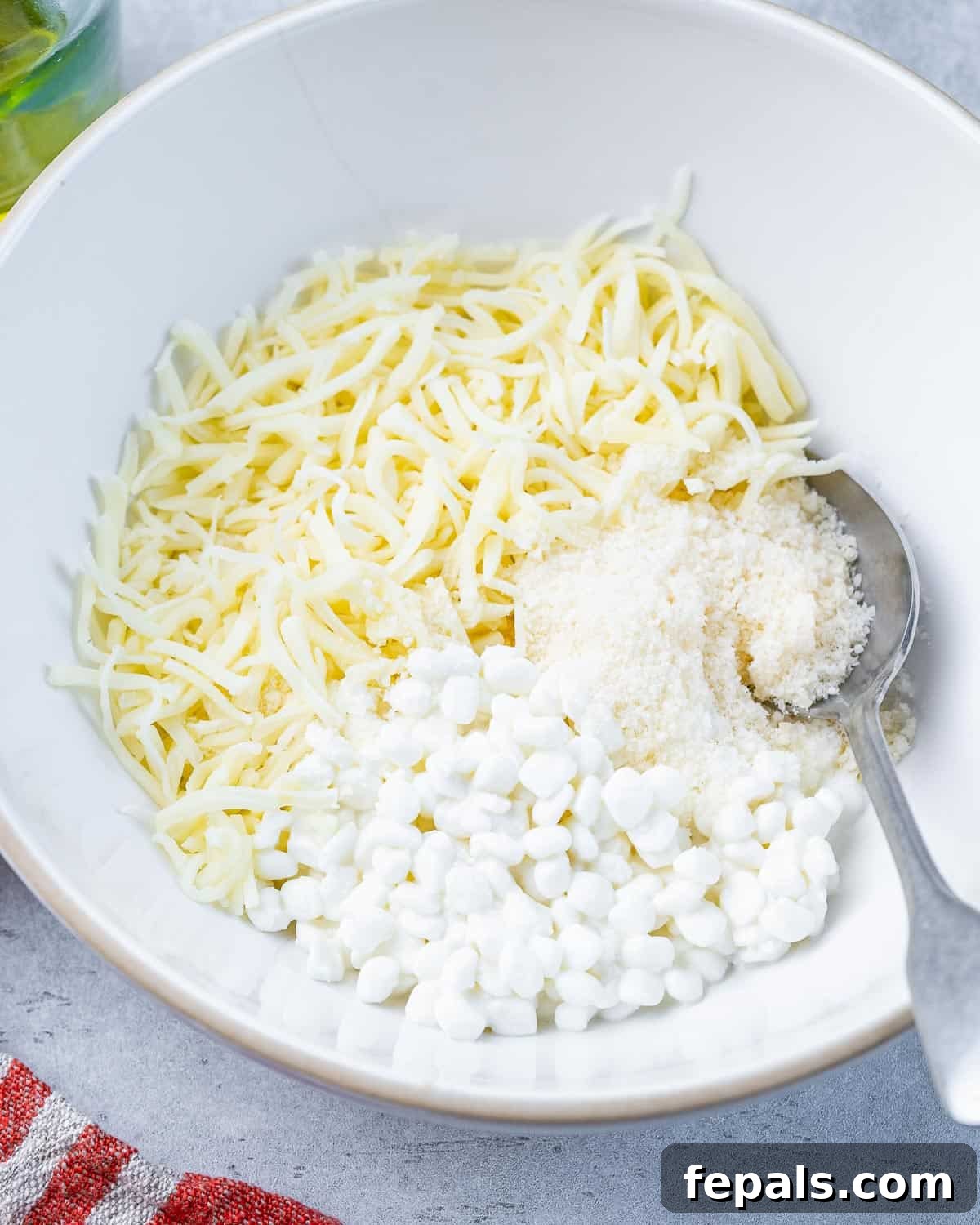 Mixing cottage cheese, mozzarella, and Parmesan cheese in a large bowl to create the creamy layer for Million Dollar Spaghetti.