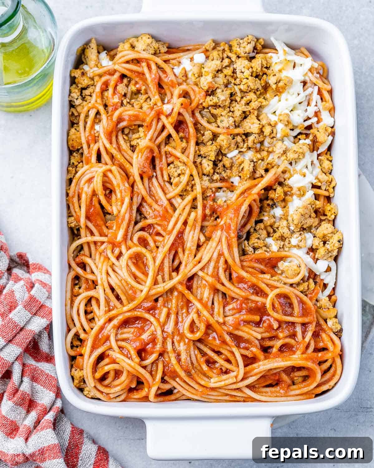Assembling layers of spaghetti, cheese mixture, and meat sauce in a casserole dish for Million Dollar Spaghetti.