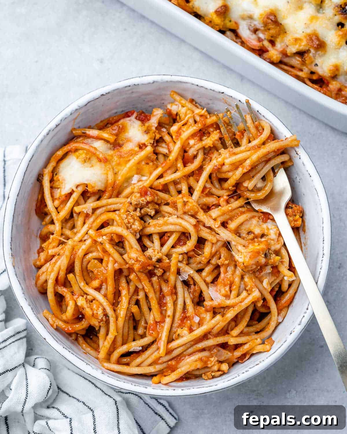 A perfectly portioned serving of Million Dollar Spaghetti in a white bowl, ready to be enjoyed with a fork.