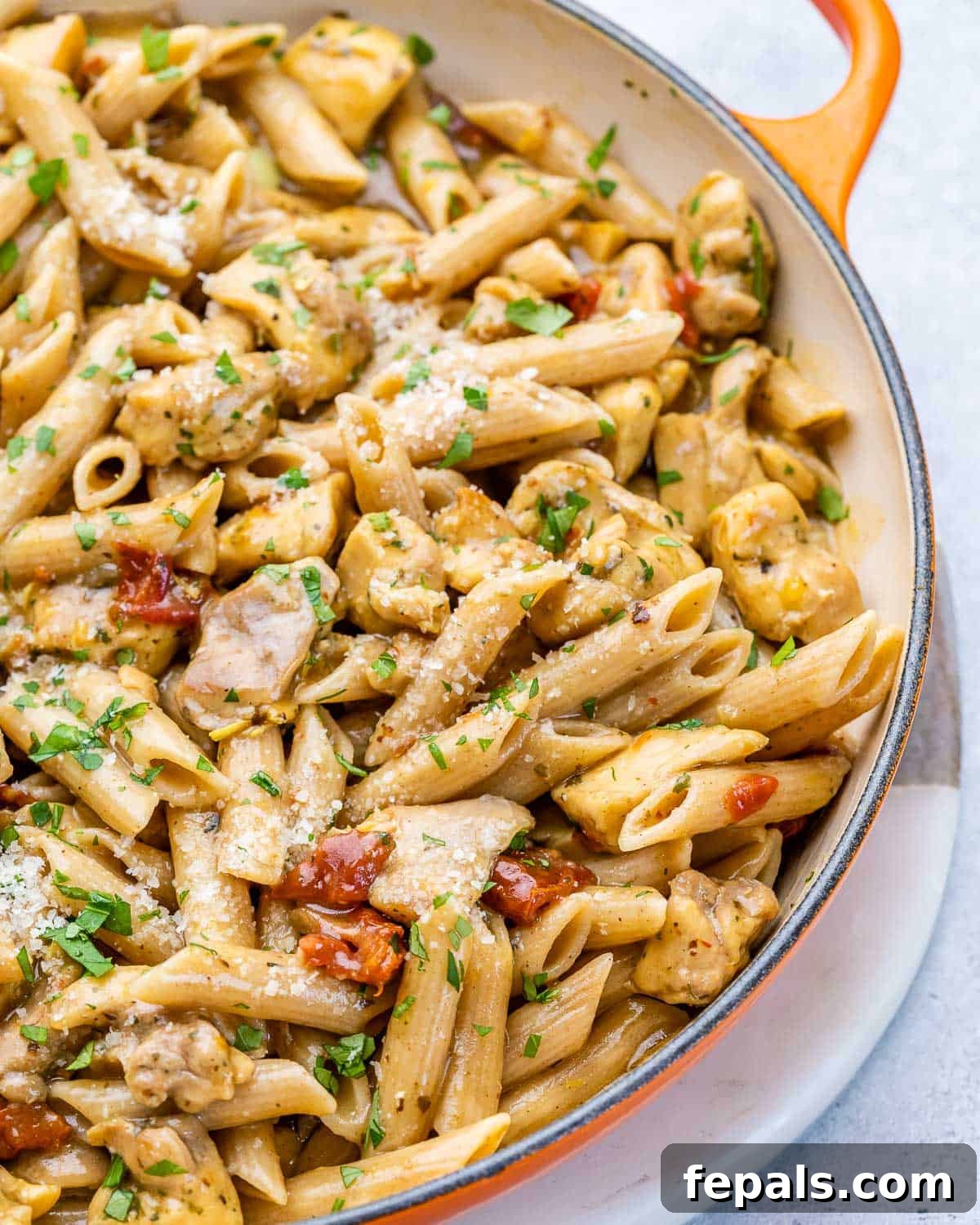 Close-up top view of the creamy chicken penne pasta in a rustic skillet, ready to serve.