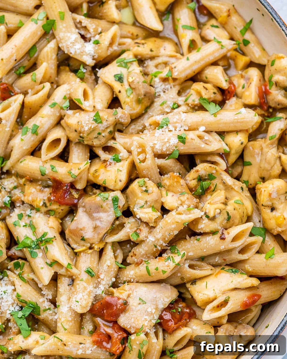 Close-up view of rich, creamy chicken and pasta in a skillet, showcasing its appealing texture and color.