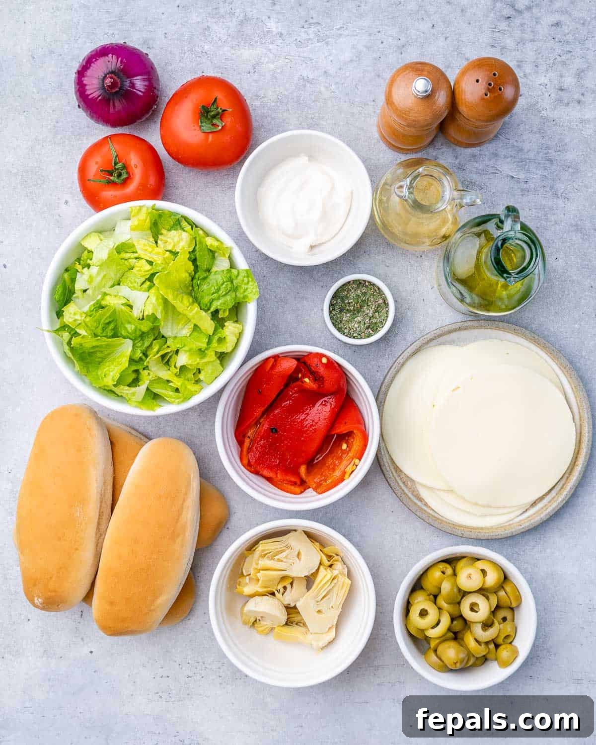Ultimate Chopped Italian 4 Bowl of lettuce near fresh tomatoes, roasted red pepper, artichokes and seasonings.
