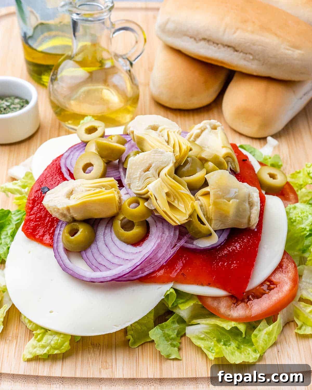 Ultimate Chopped Italian 6 Lettuce piled with tomato slices, cheese slices, roasted red pepper, red onions, olives and artichokes.