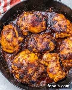 Smoky Chipotle Al Pastor Chicken 10 cooked chicken al pastor thighs in a dark round skillet.