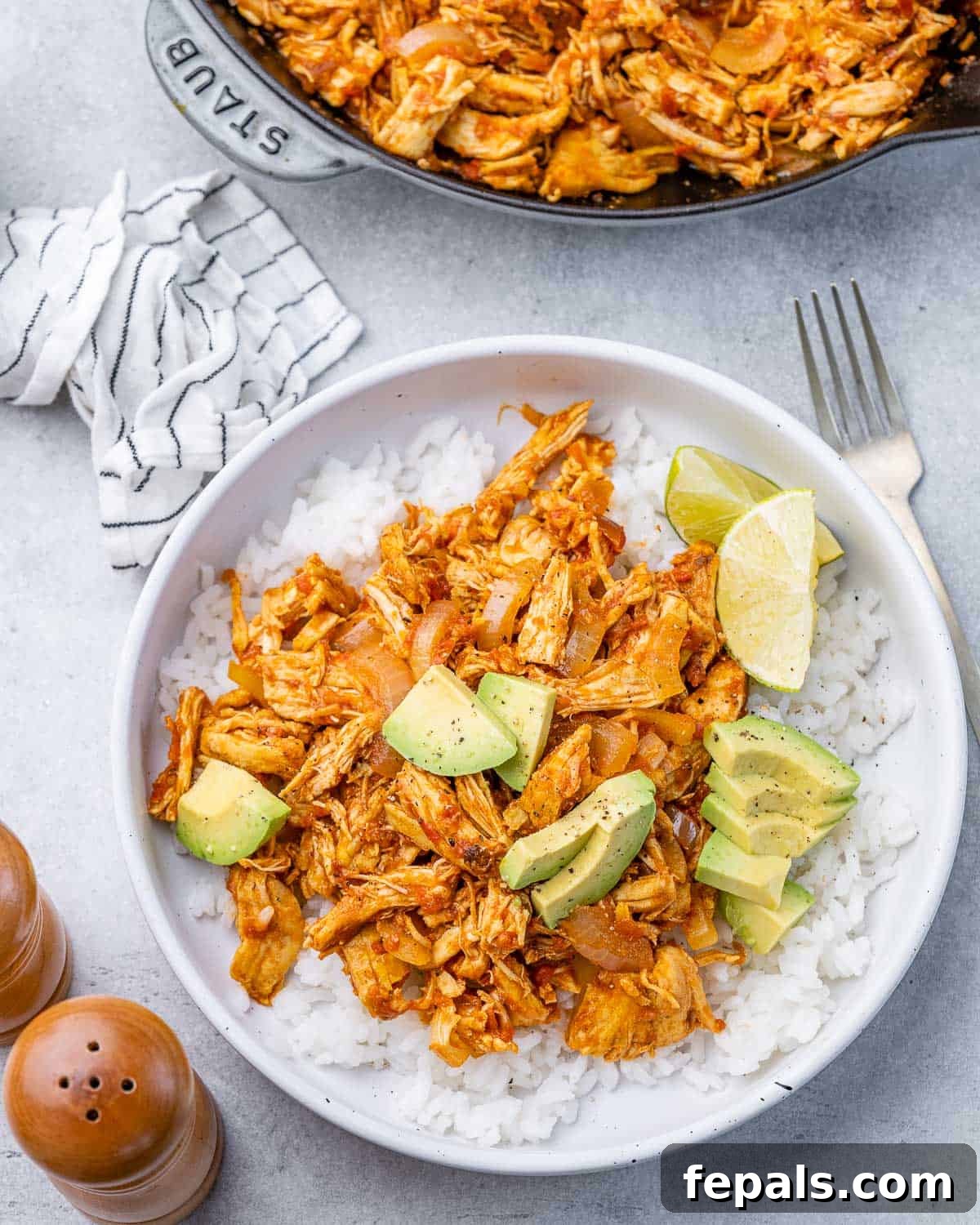 The Ultimate Chicken Tinga 8 A perfectly plated bowl of Chicken Tinga, generously served with fluffy rice, vibrant fresh lime wedges, and creamy chopped avocado, ready to be enjoyed.
