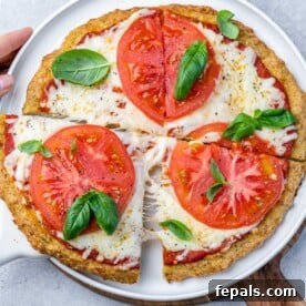 chicken crusted pizza with melted cheese and sliced red tomatoes, garnished with fresh basil leaves.