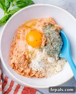 Mixing egg with ground chicken and seasonings in a white bowl.