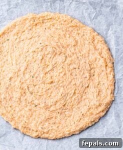 Pizza dough on a pan with parchment paper.