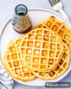 Overhead shot of four stacked chaffles served on a round white plate, ready to enjoy.