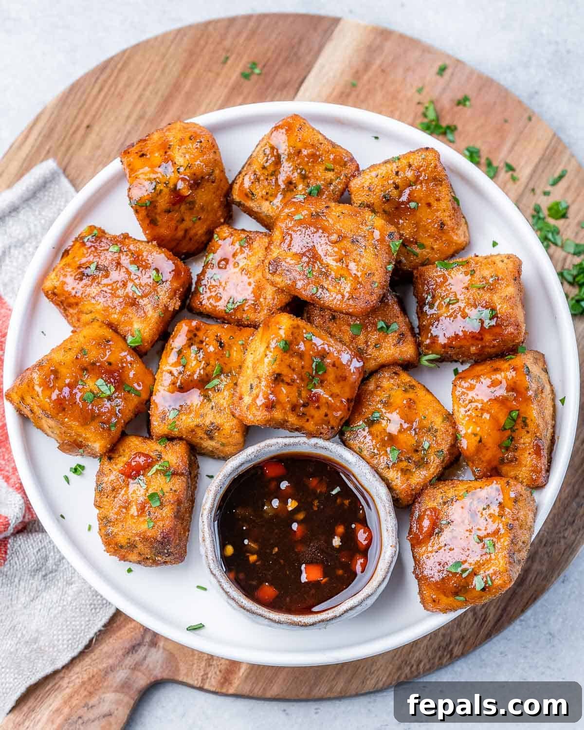 Top view salmon bites on a plate with a small bowl of sauce.