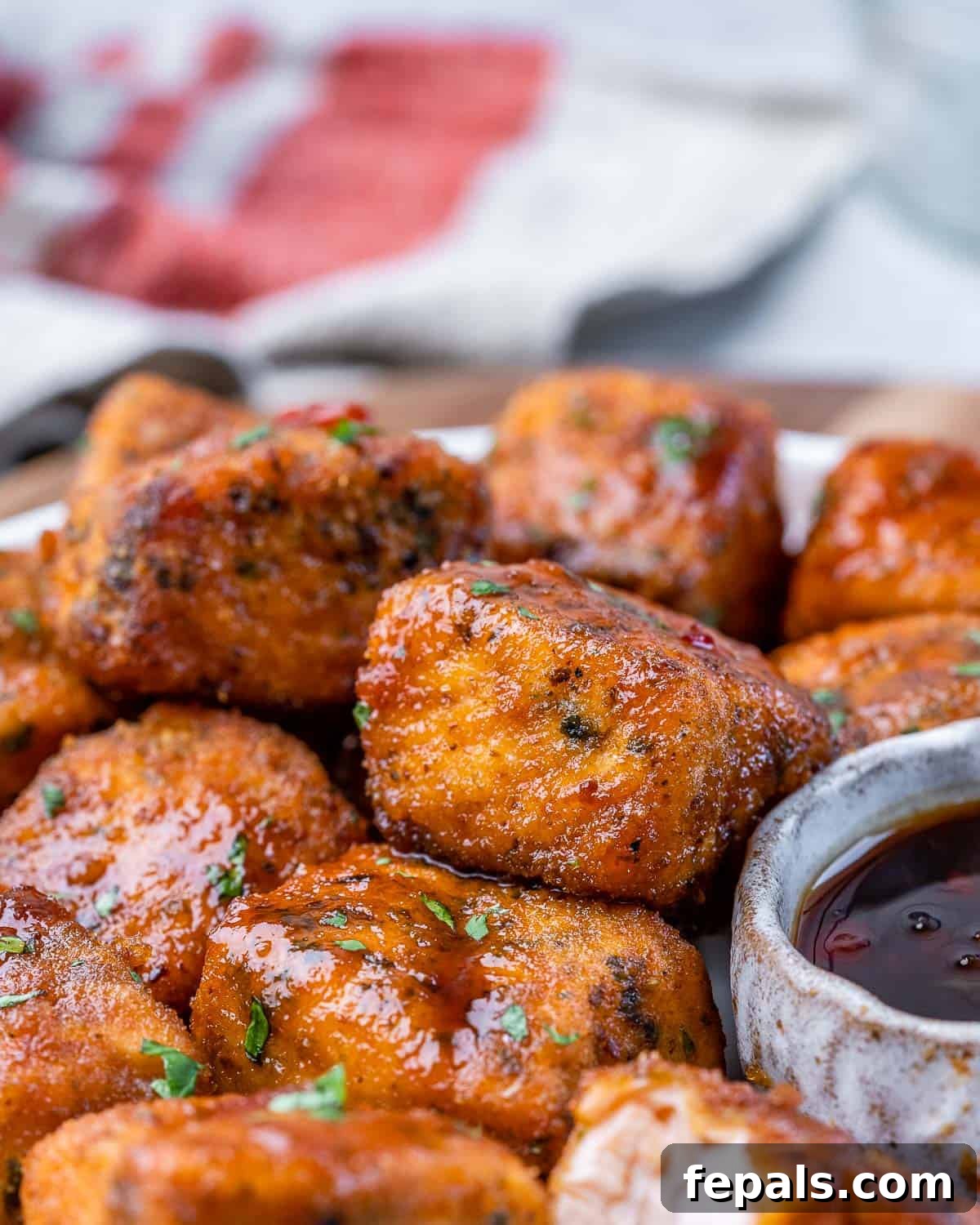 side shot of salmon bites on a dish next to dipping sauce 