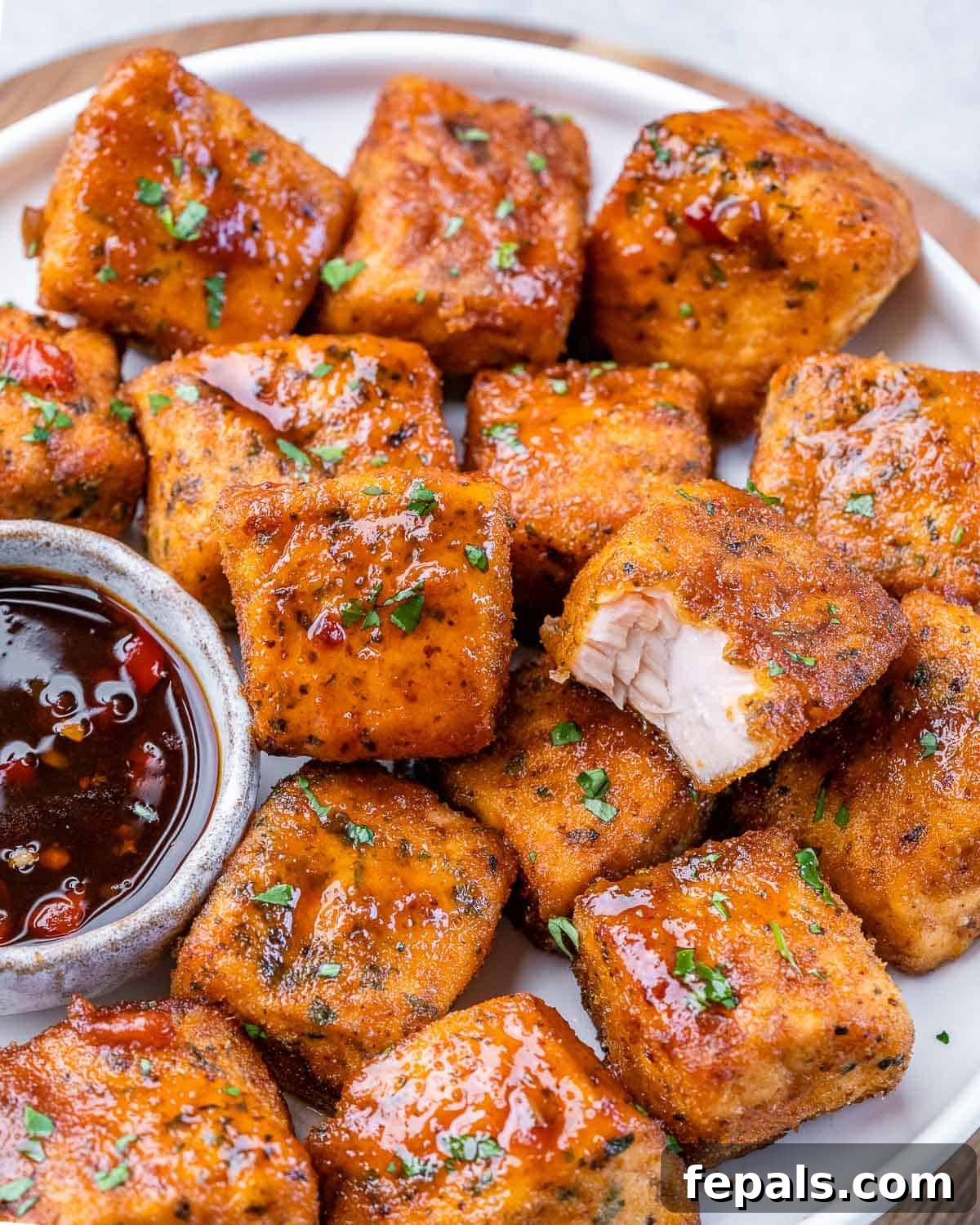 Air fryer salmon bites stacked on a white plate.