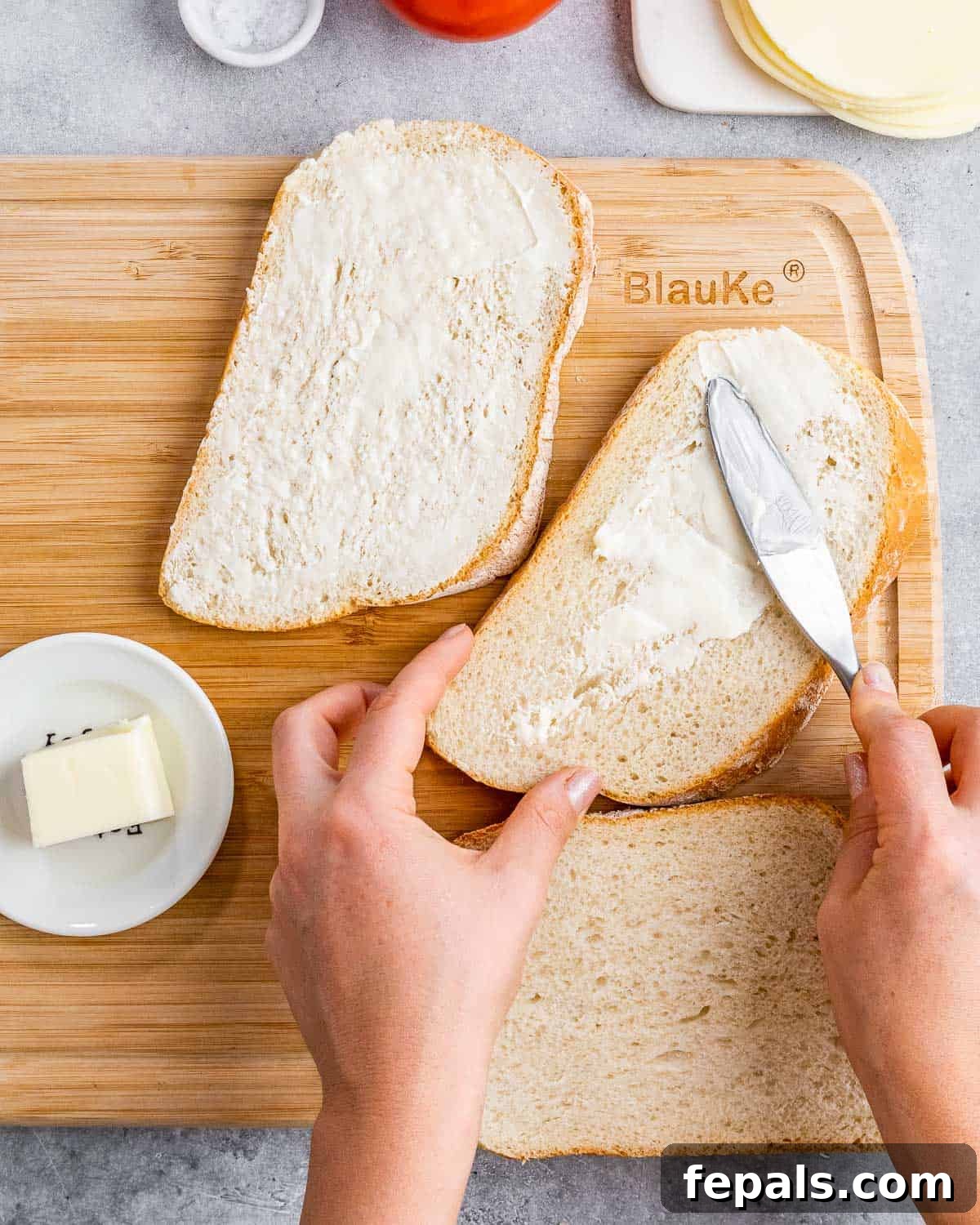 Spreading softened butter evenly on one side of bread slices.