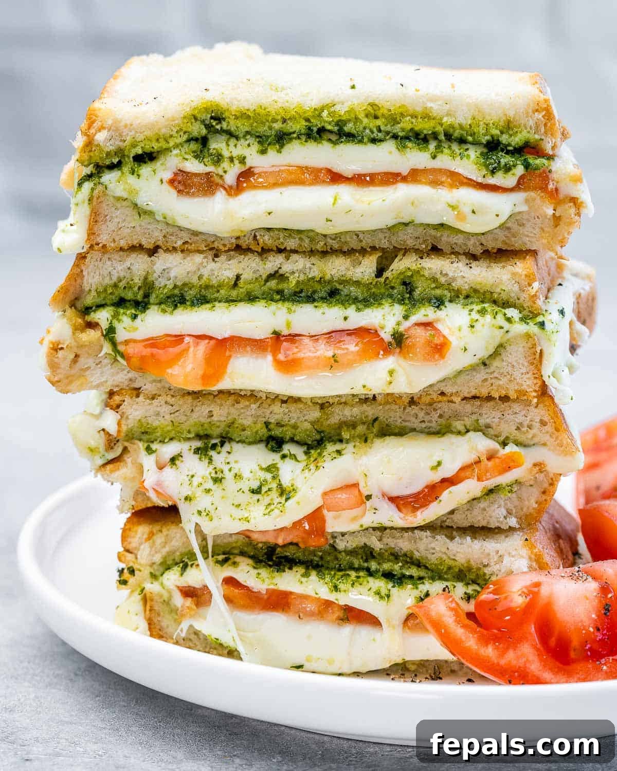 Two air fryer grilled cheese sandwiches, sliced in half and stacked on a white plate, showcasing the crispy exterior and melty filling.